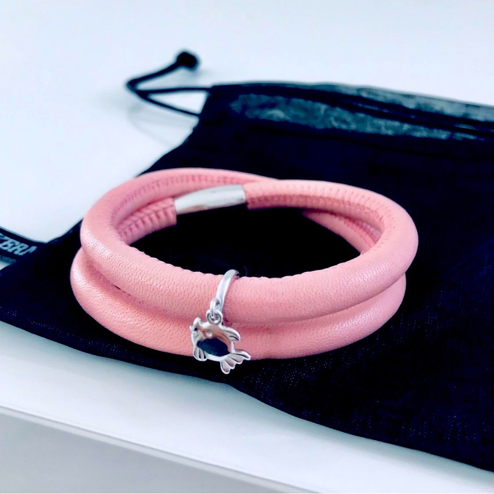 Leather pink bracelet with silver dangling charm and jewelry pouch.